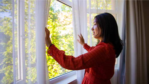 Lady looking out of an open window. Is it good to sleep with open window?