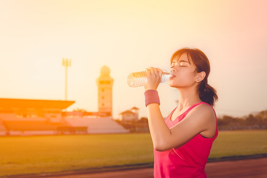 well-rested woman drinks from a water bottle during a jog