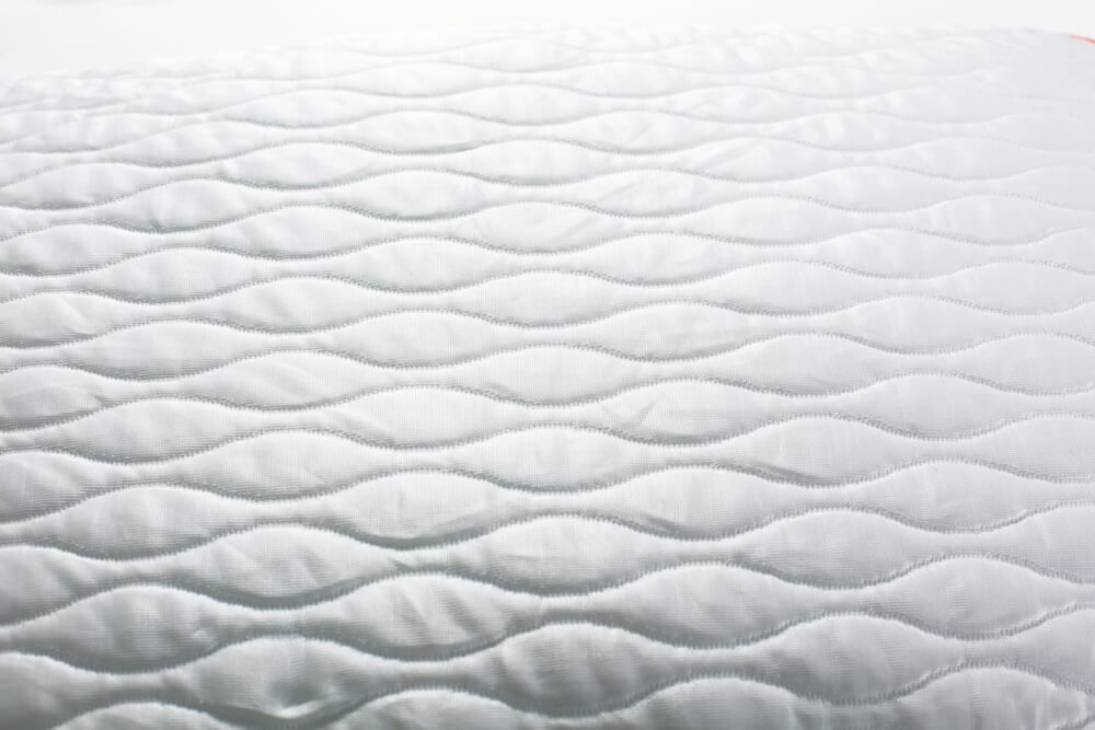 White fabric with wavy stitched design to depict MLILY fabric safety standards.