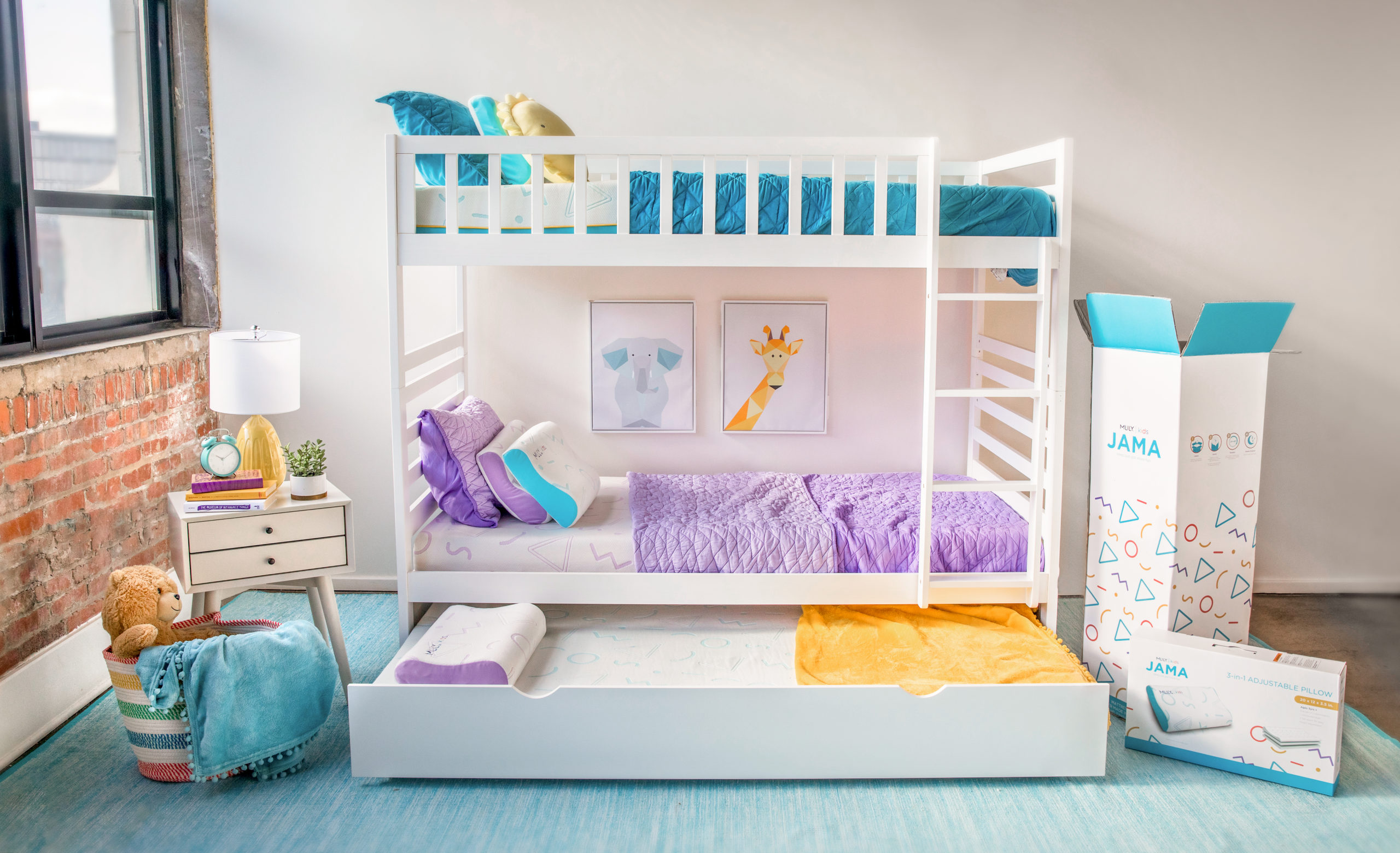 Kids bedroom with a bunk bed and trundle extended with purple and teal bedding; large MLILY box, bedside table, and toy basket with a stuffed bear.