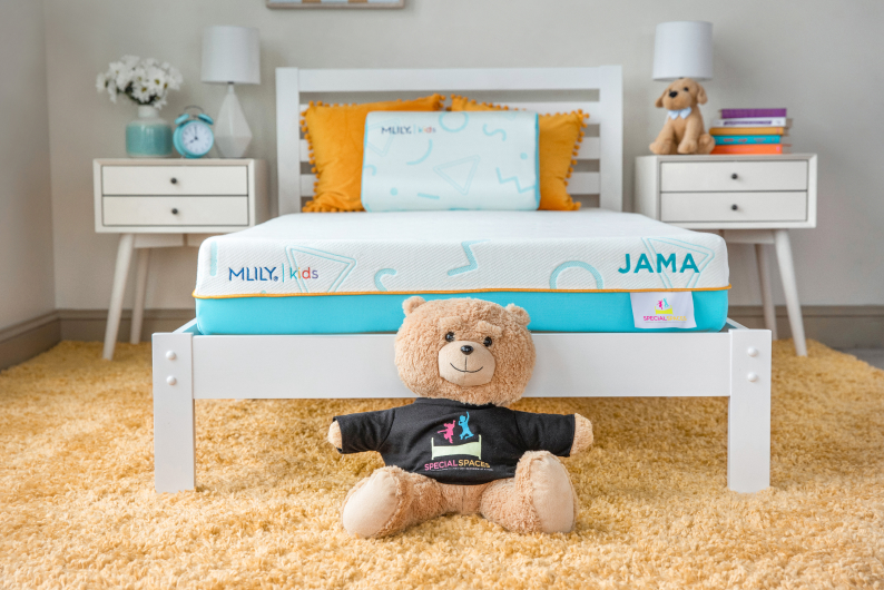 Stuffed bear sitting at foot of MLILY JAMA kids mattress on white bedframe between two bedside tables.