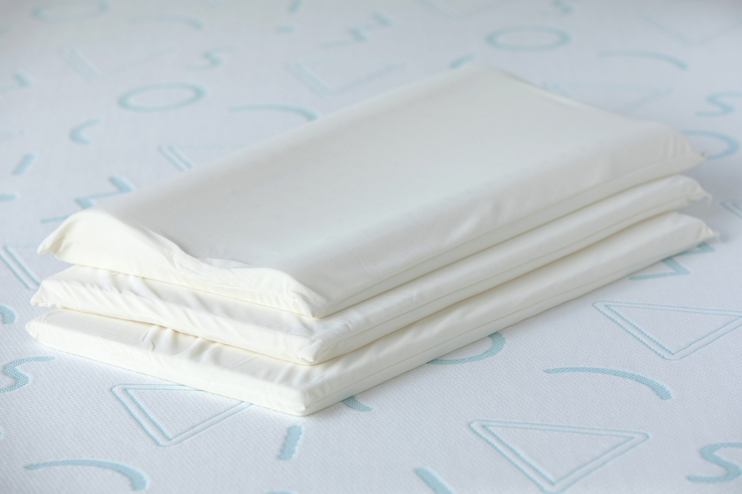 The Jama pillow’s three memory foam layers in off white covers sit on Jama mattress to show the inside contents of the pillow.