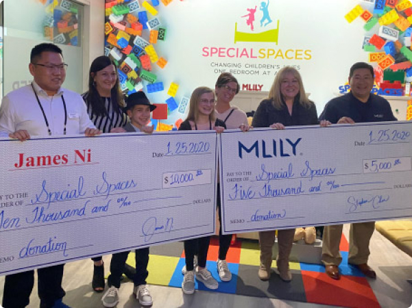 MLILY and company founder James Ni present giant checks with donations to Special Spaces nonprofit.
