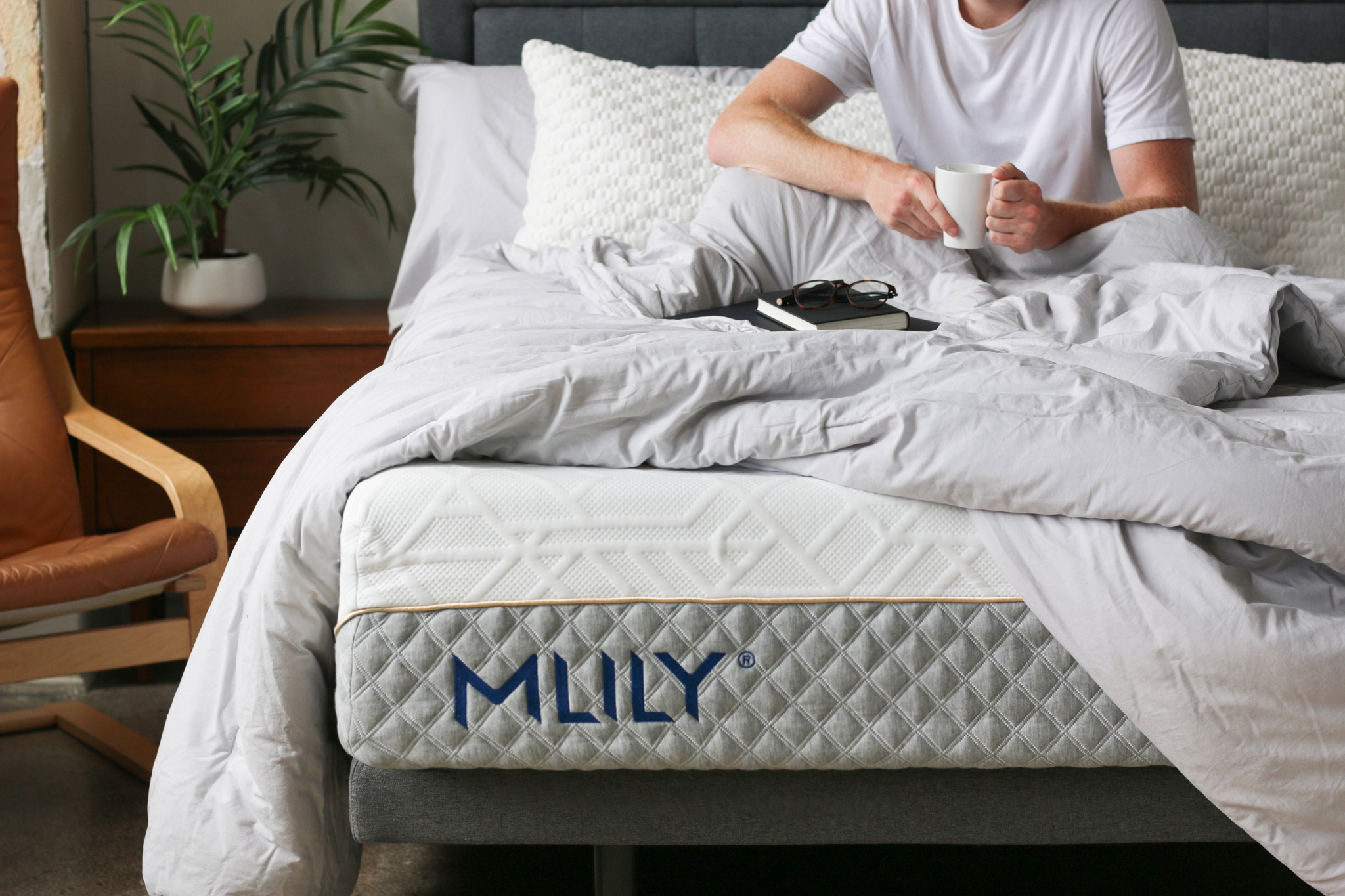 Man sitting on a purpose built MLILY mattress with a coffee mug