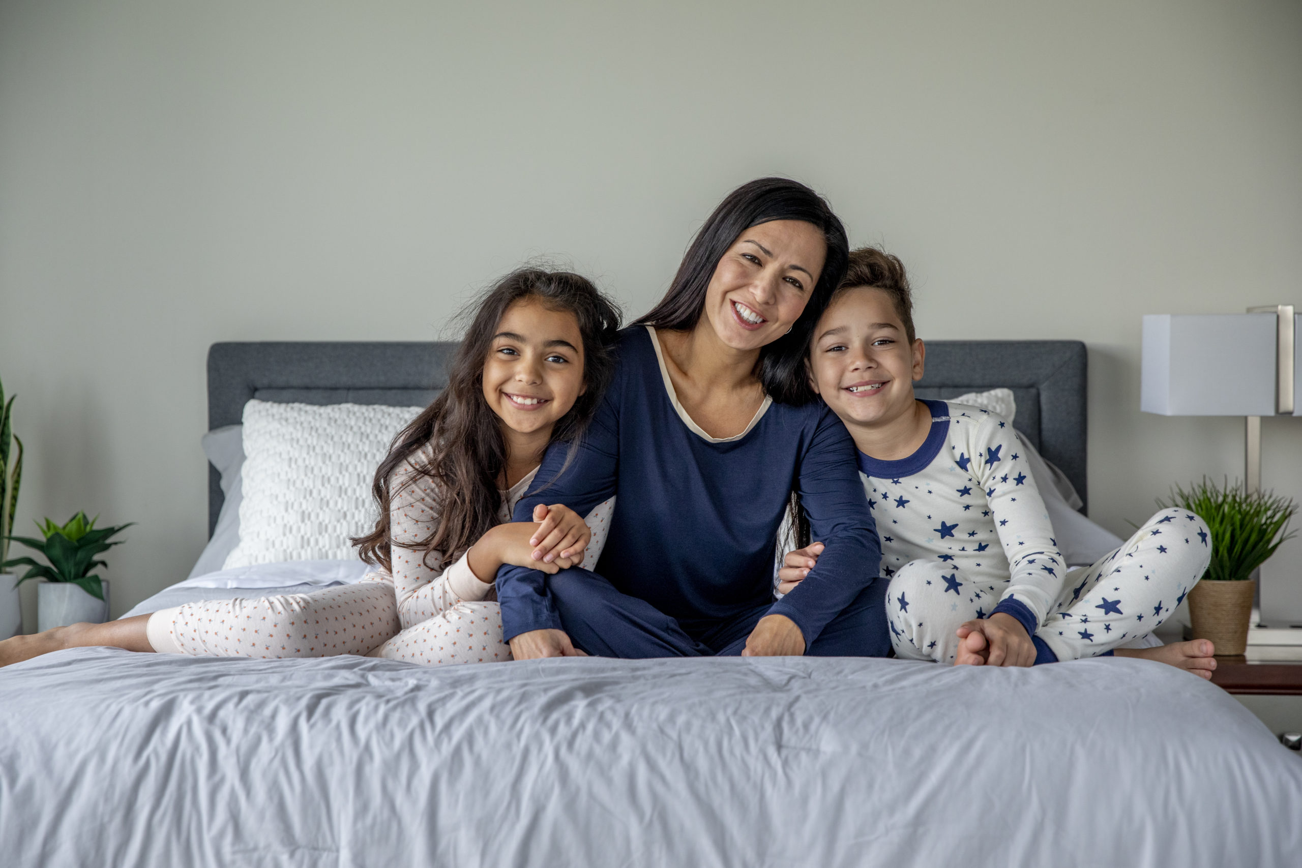 Mom, son, and daughter smiling for a photo on a mattress