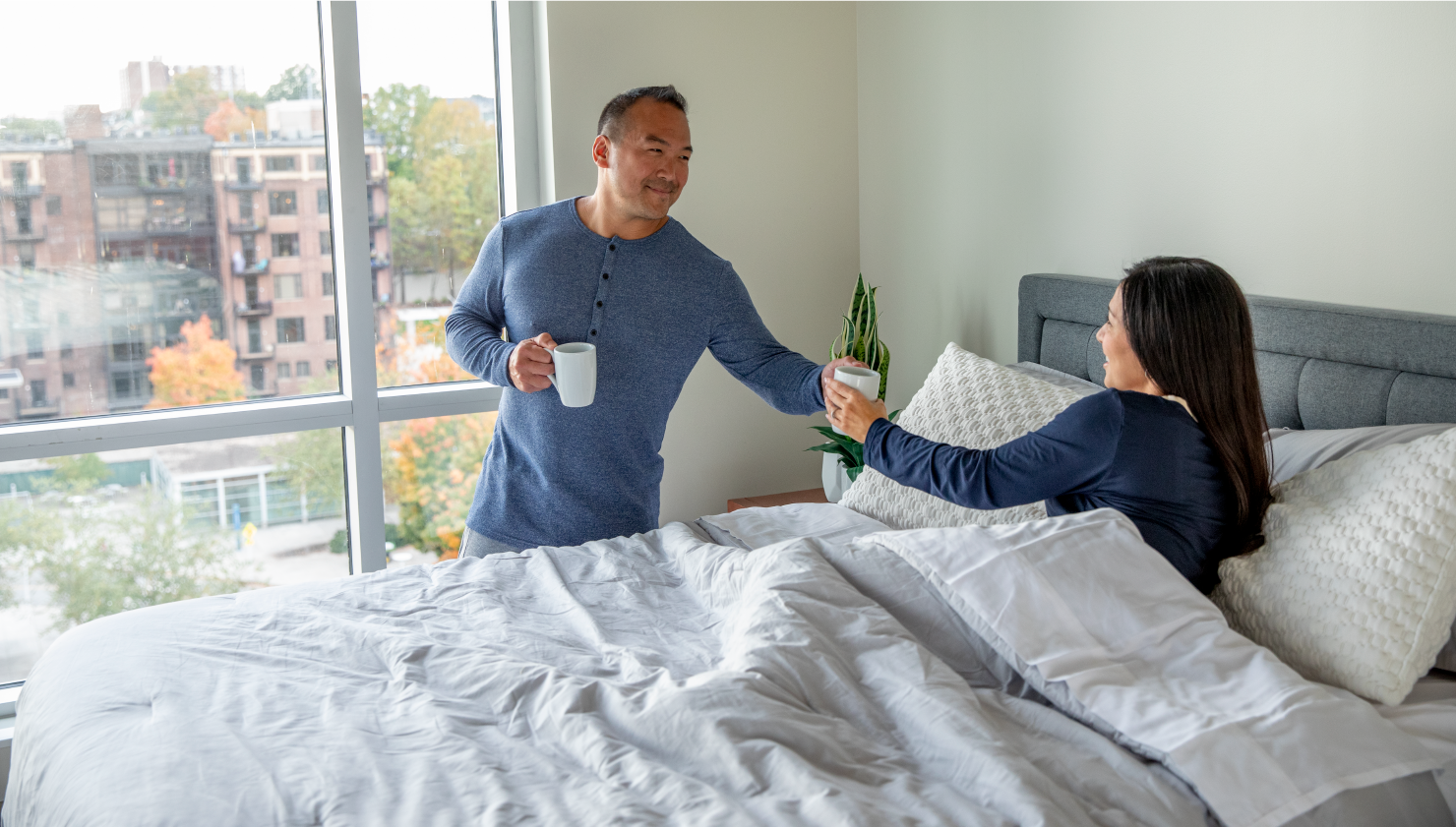 Man handing woman in bed a cup of coffee
