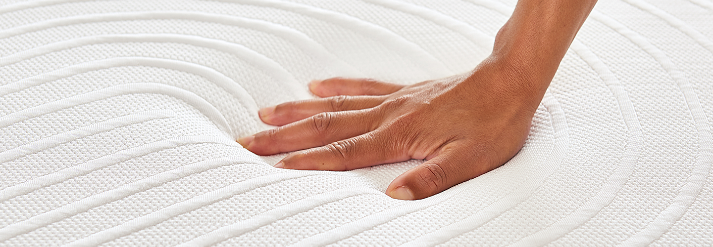 Hand pressing down on mattress