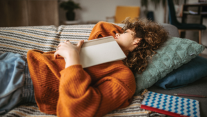 Woman sleeping with book on her during naptime in bed